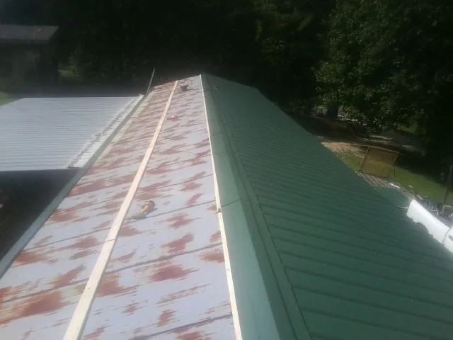 Old rusted panels beside newly installed green metal roofing — Wind Damage Roof Repair by Roofing Brothers in Fox Lake