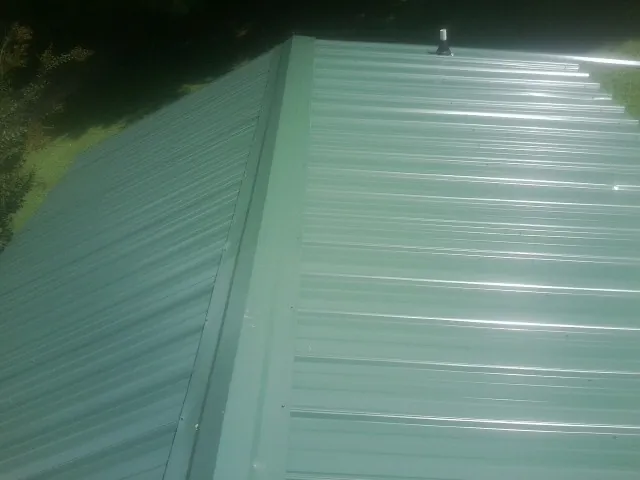 New green metal panels meeting at the ridge of a roof in Fox Lake