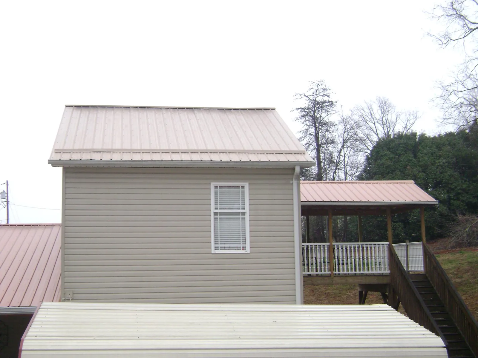 Tan metal roofs on a two story addition and attached porch, from a Roof Replacement job in Fox Lake