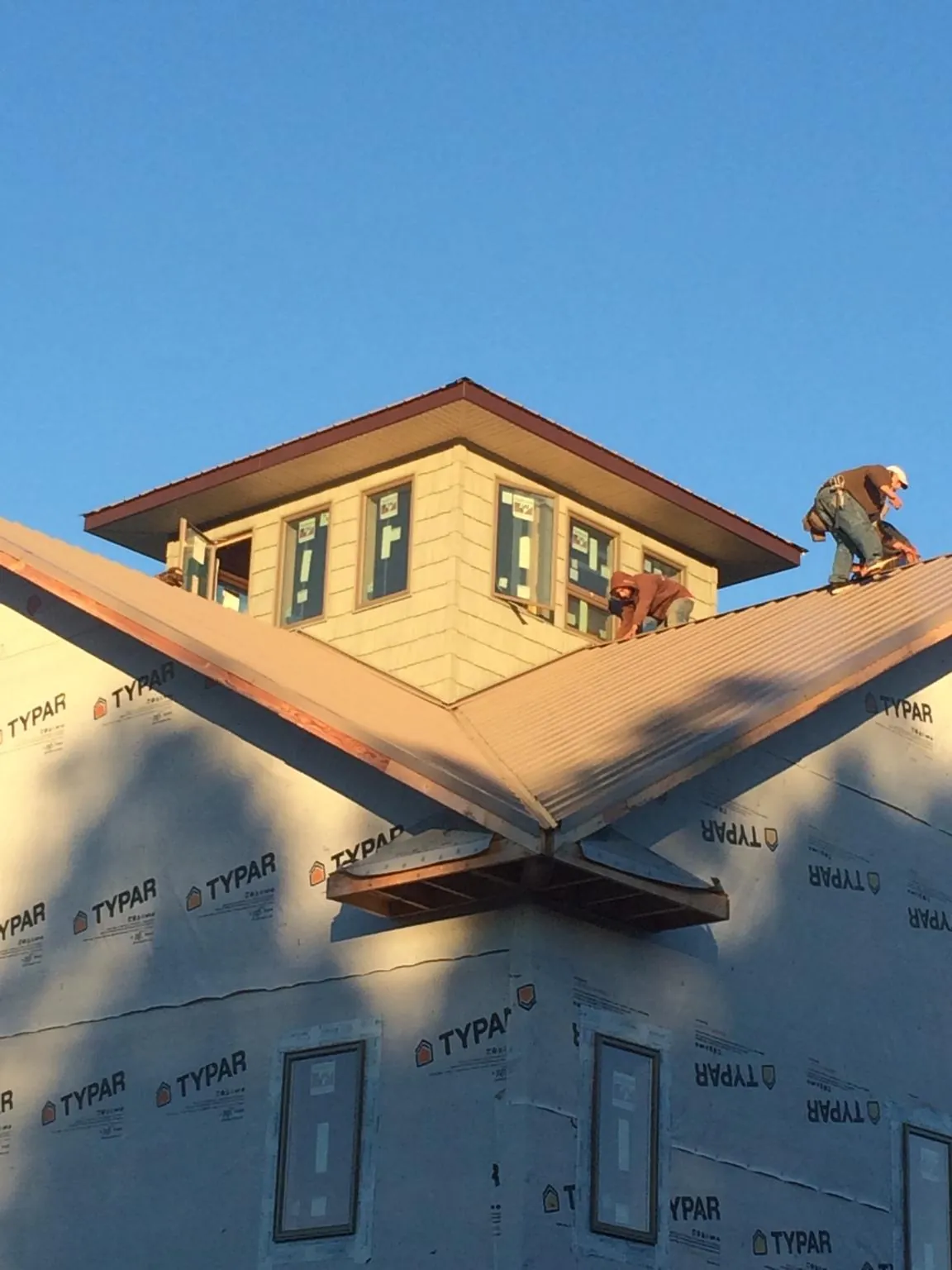 Roofers working around a rooftop cupola on a new metal roof at sunset — Roof Waterproofing in Fox Lake by Roofing Brothers